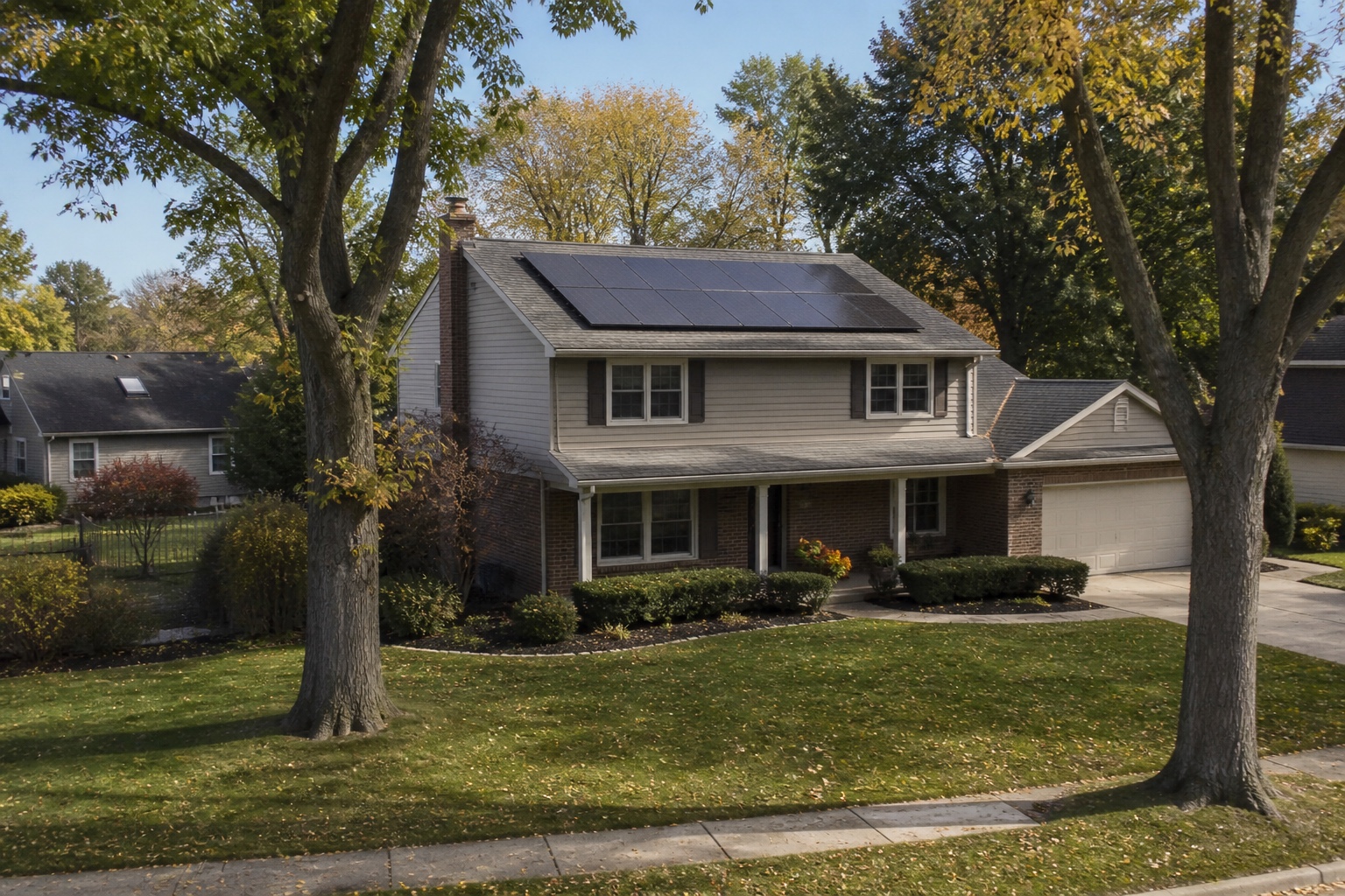 Two-story Northern Illinois home with rooftop solar panels framed by mature oak trees