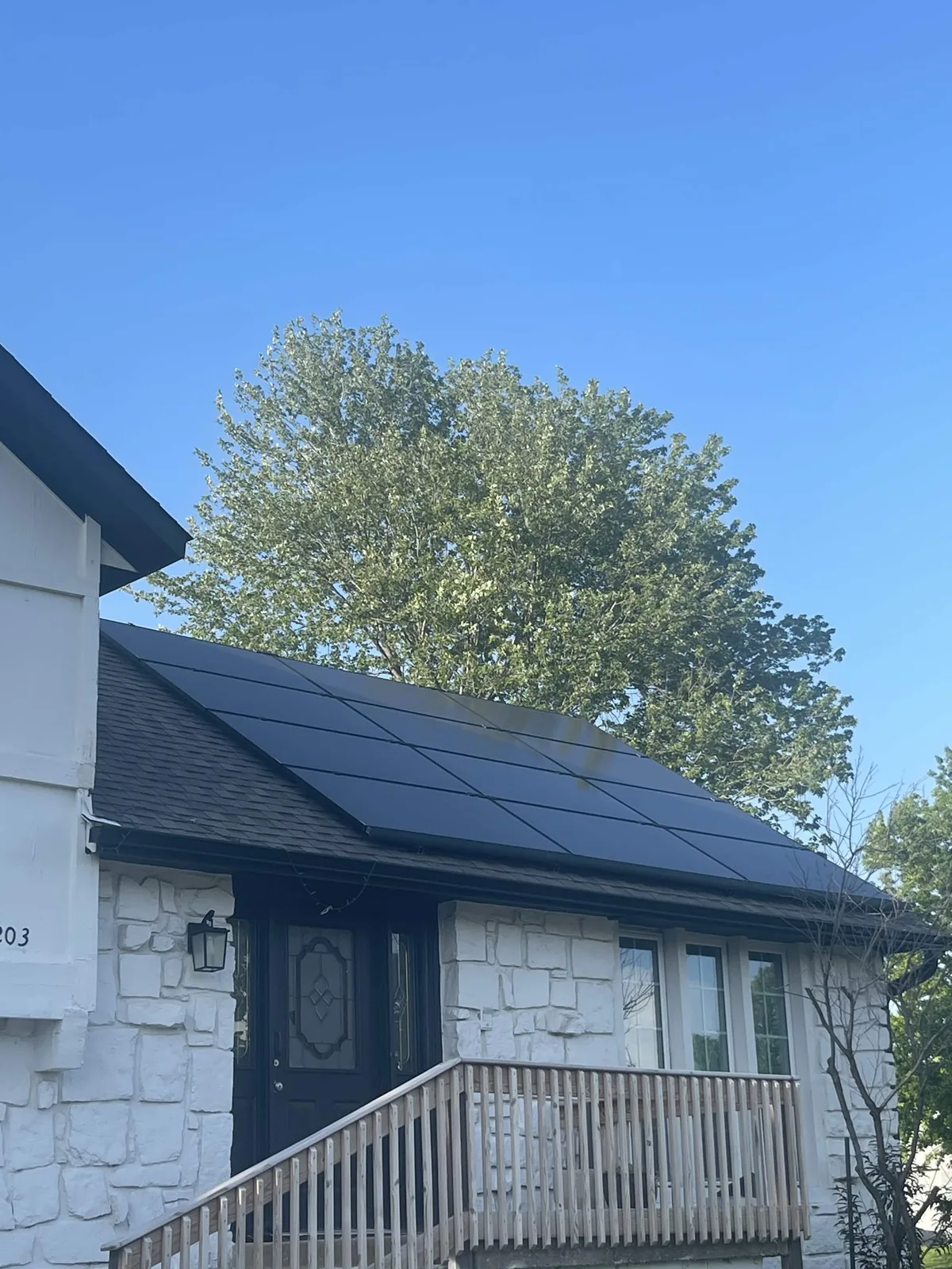White stone Illinois home with black rooftop solar panels from a Direct Solar Pros project